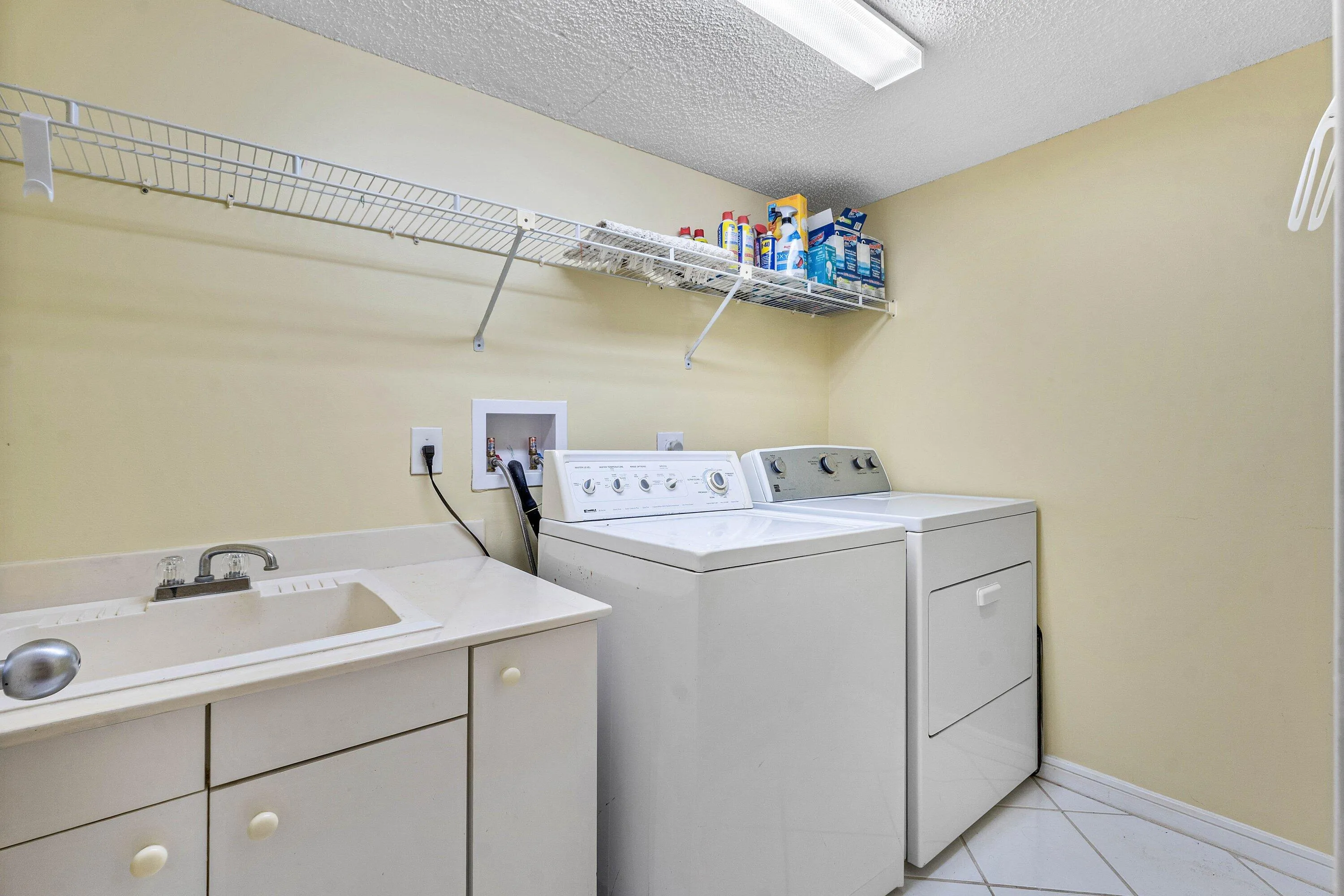 Dedicated in-unit laundry includes full-size washer and dryer, utility sink and open shelving.