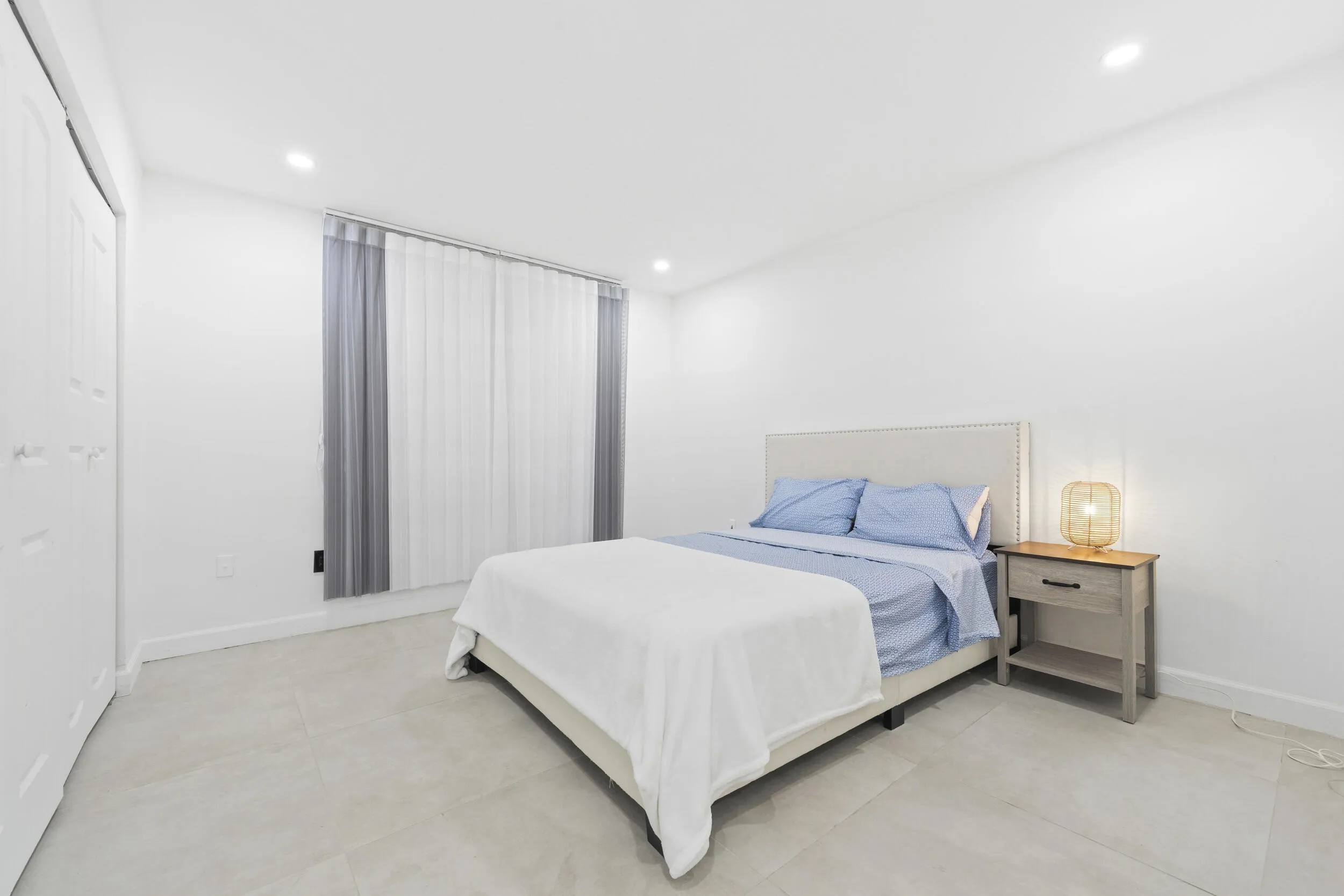 Recessed lighting, light-toned tile flooring, vertical blinds, and a white paneled closet door