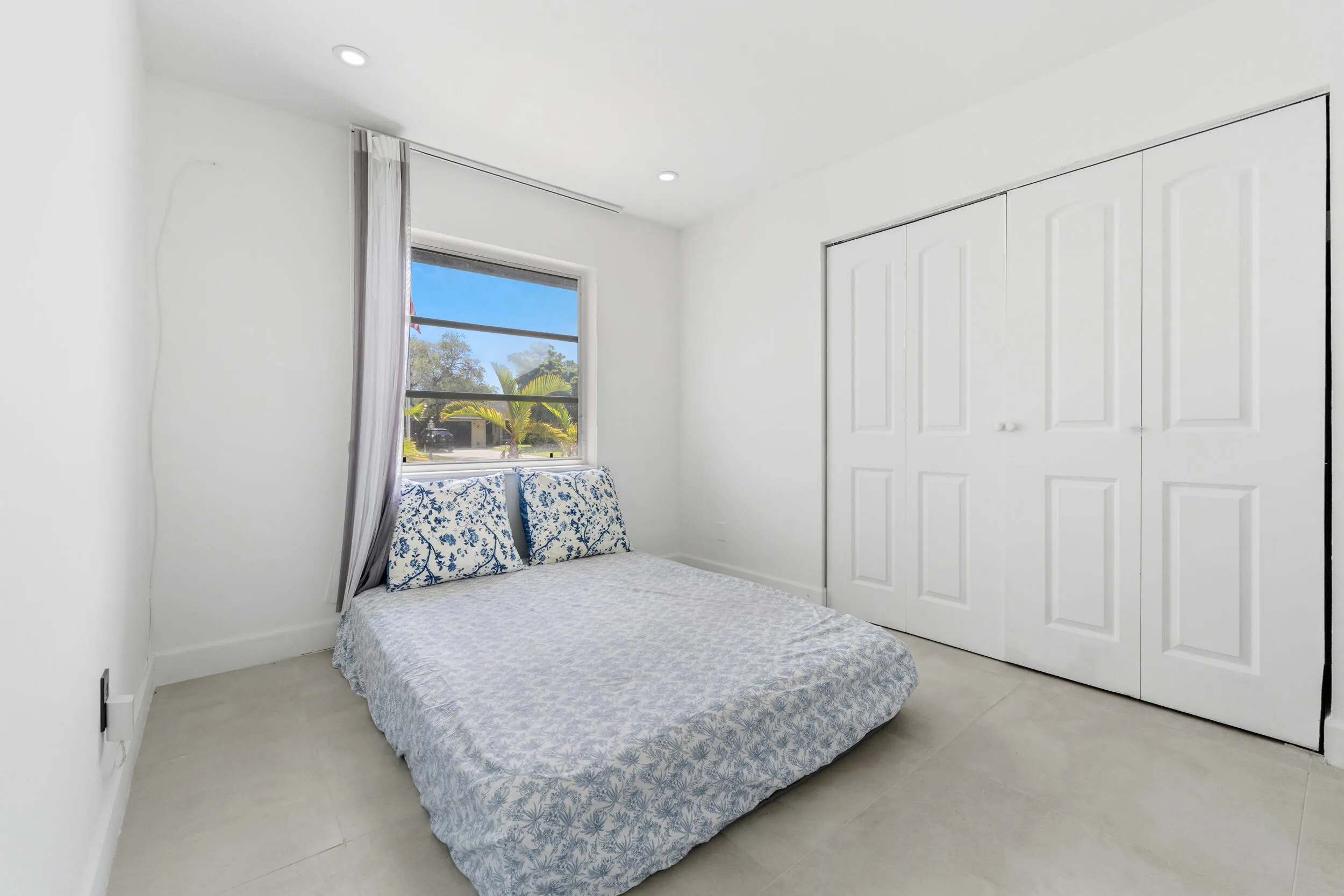 Recessed lighting, light-toned flooring, white painted walls, and a window with outdoor scenery