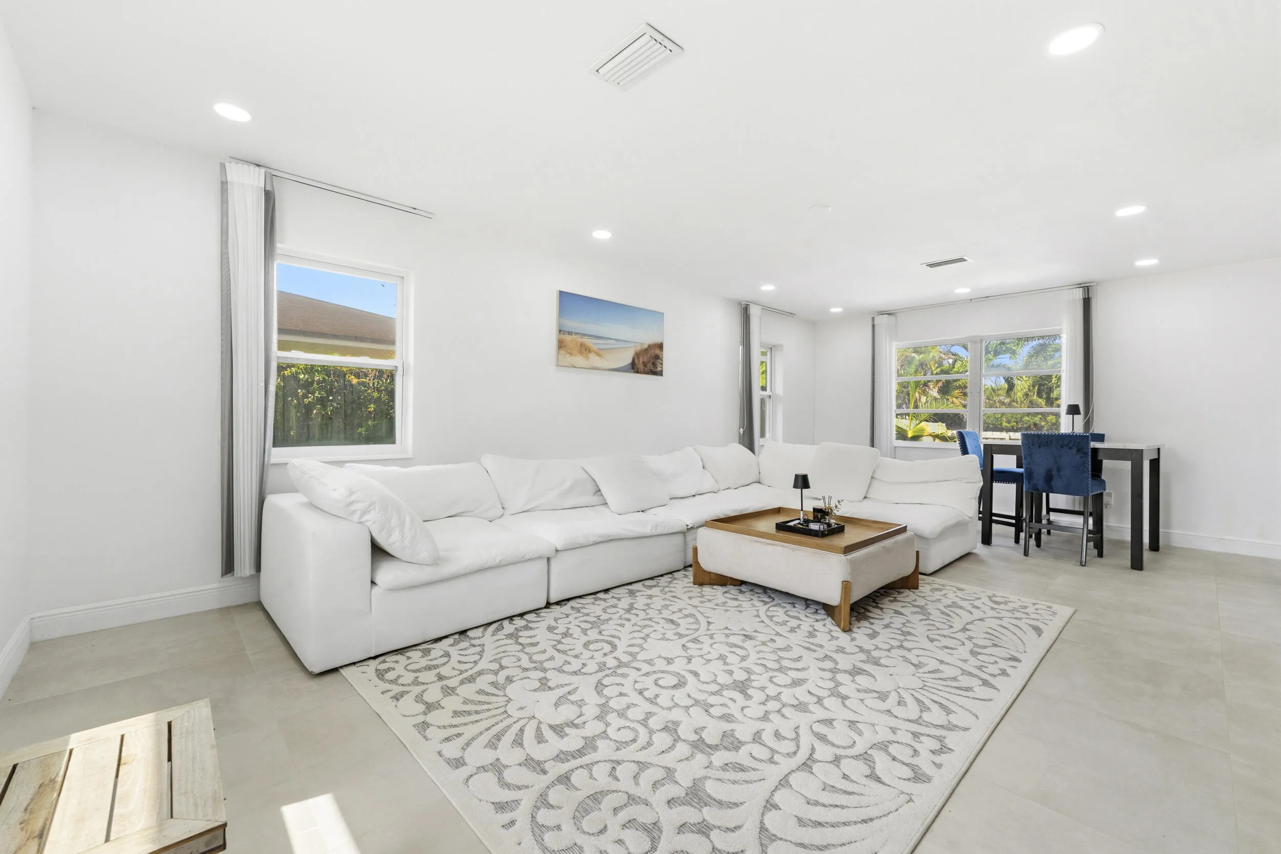 Recessed lighting, light-toned tile flooring, and multiple windows with white trim