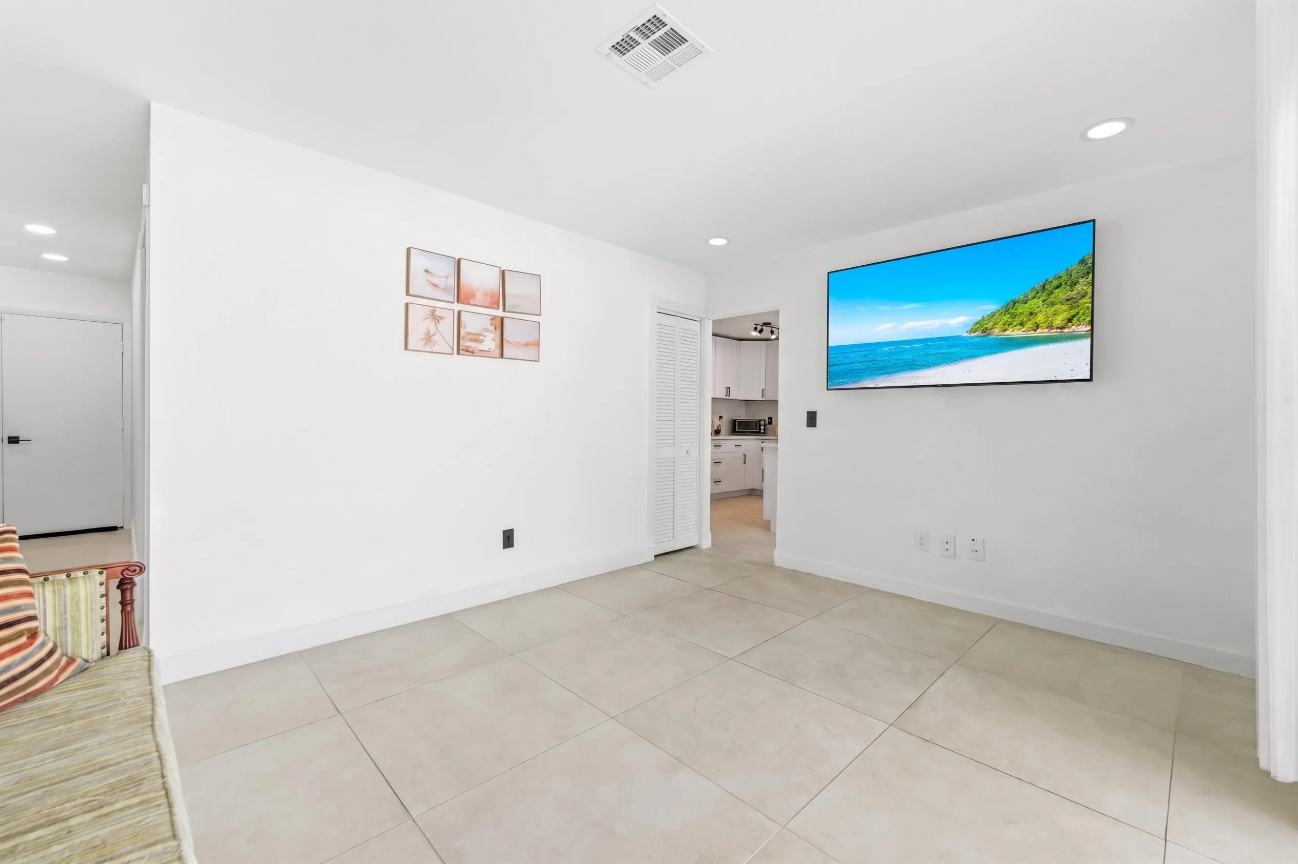 Recessed lighting illuminates the neutral tile flooring and white walls