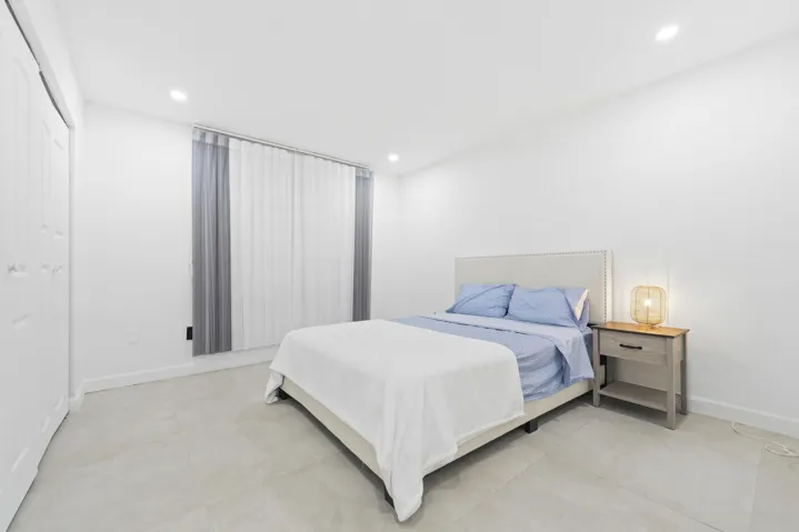 Recessed lighting, light-toned tile flooring, vertical blinds, and a white paneled closet door