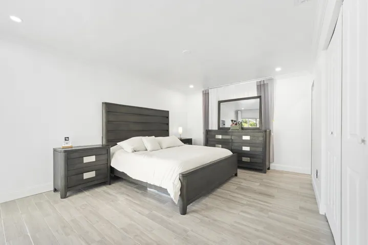 Recessed ceiling lighting illuminates the space, featuring light wood-finish flooring and white bi-fold closet doors