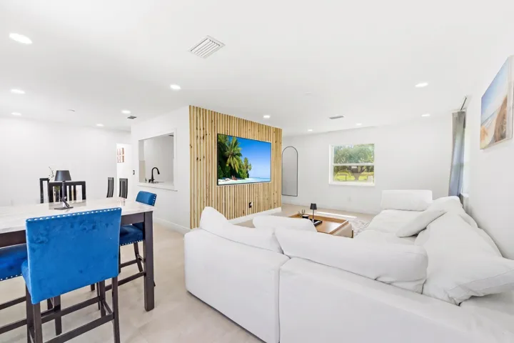 Recessed lighting throughout, white walls, wood slat accent wall, pass-through window, and light-toned flooring