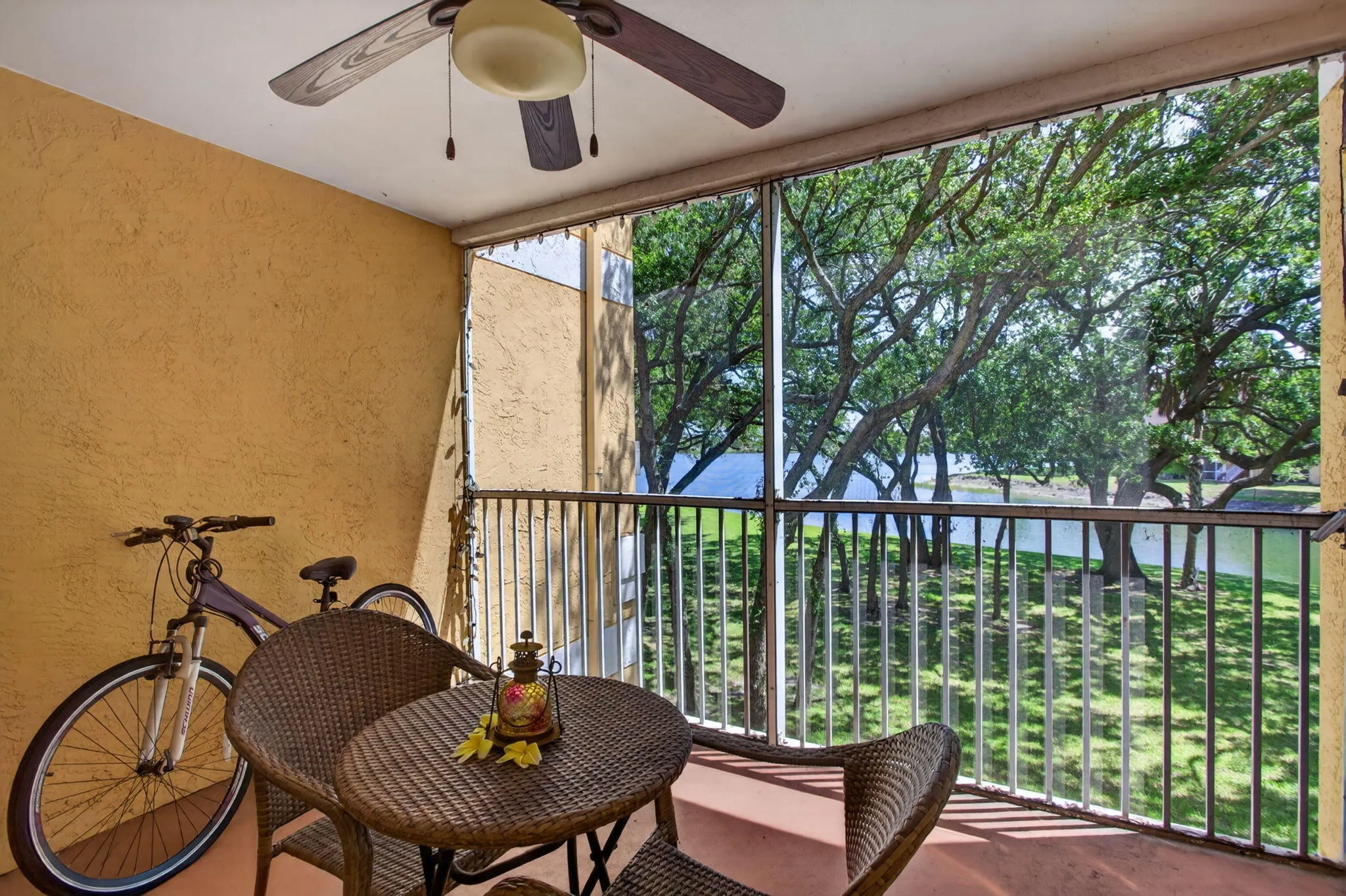 Screened balcony featuring a ceiling fan and water scenery beyond a metal railing