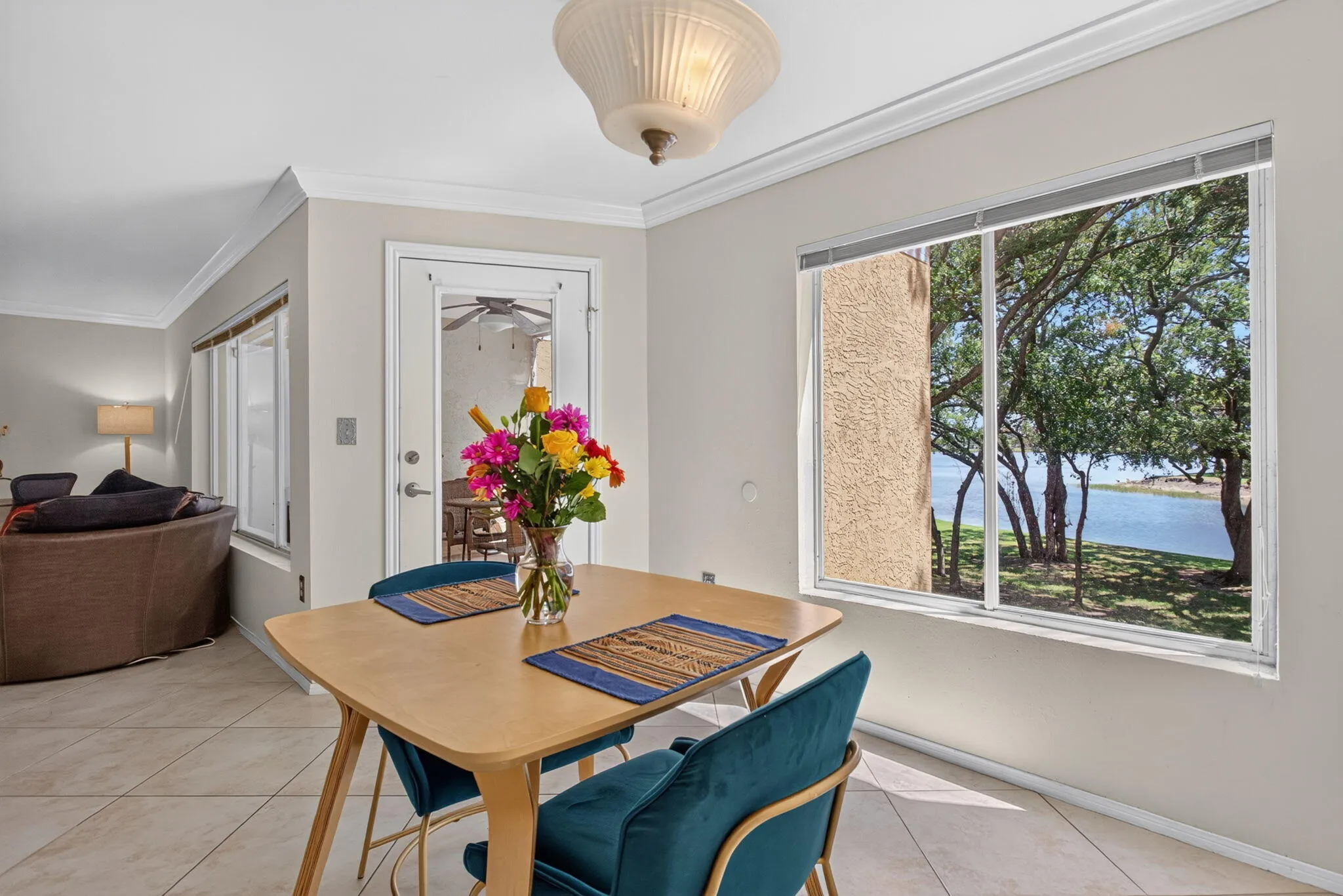 Large window with natural light, crown molding, tile flooring, and a glass-paneled door