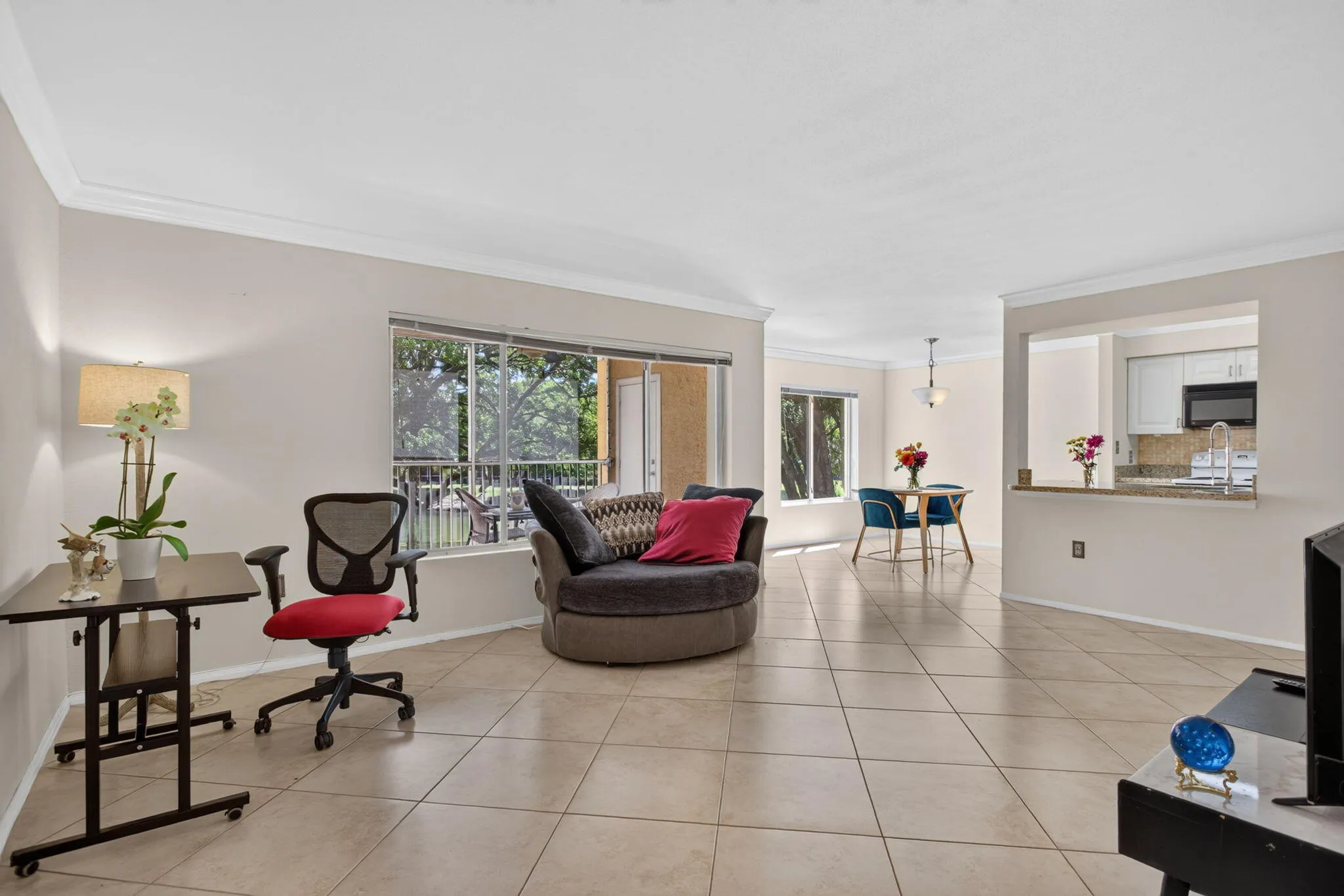 Spacious living area with tile flooring, crown molding, and large windows