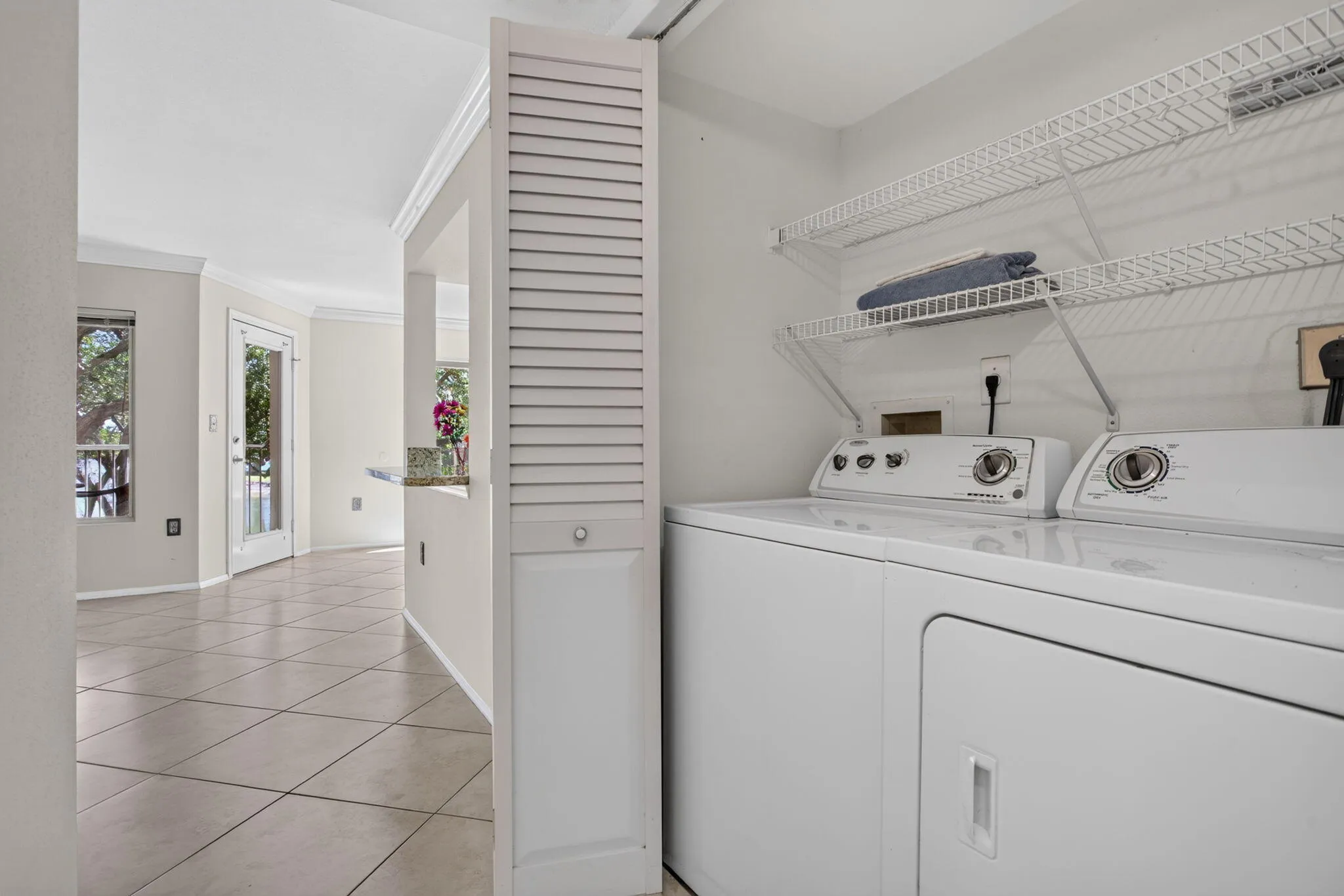 Dedicated laundry area featuring a washer and dryer, wire shelving, and louvered bifold doors