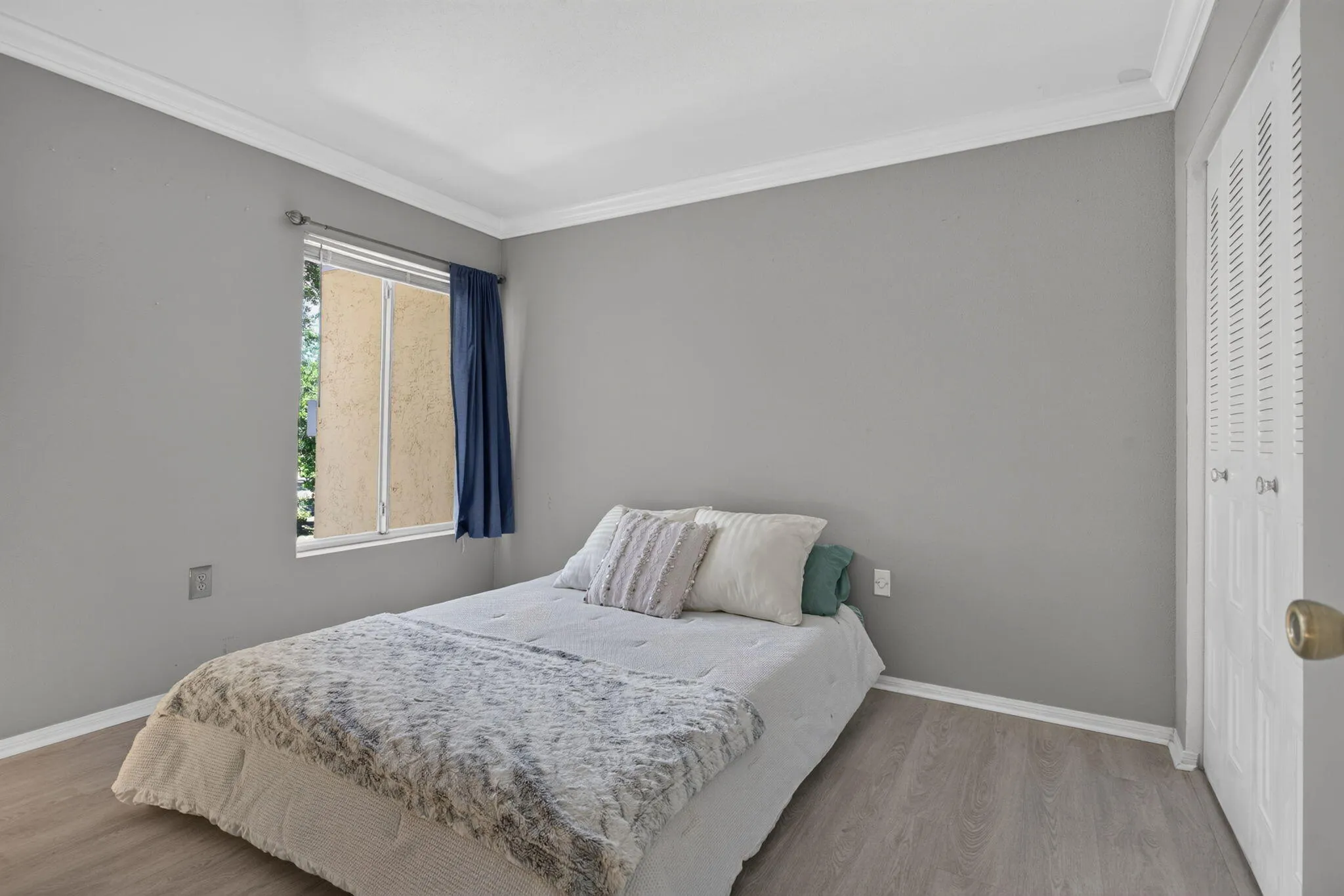 Wood-finish flooring, crown molding, and a window with natural light