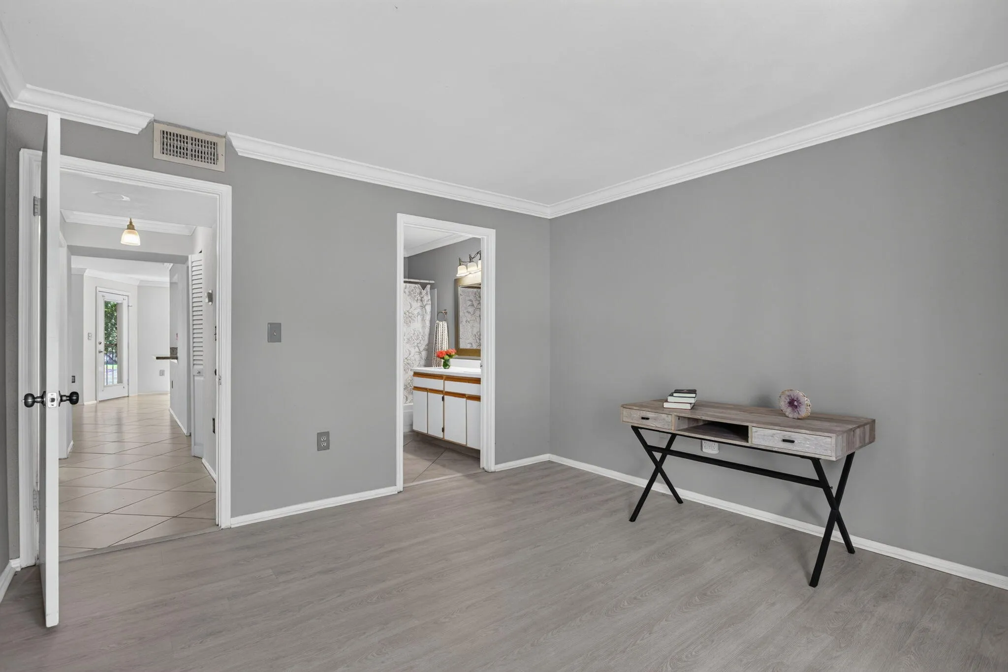 Wood-finish flooring, crown molding, and a bathroom with a white vanity