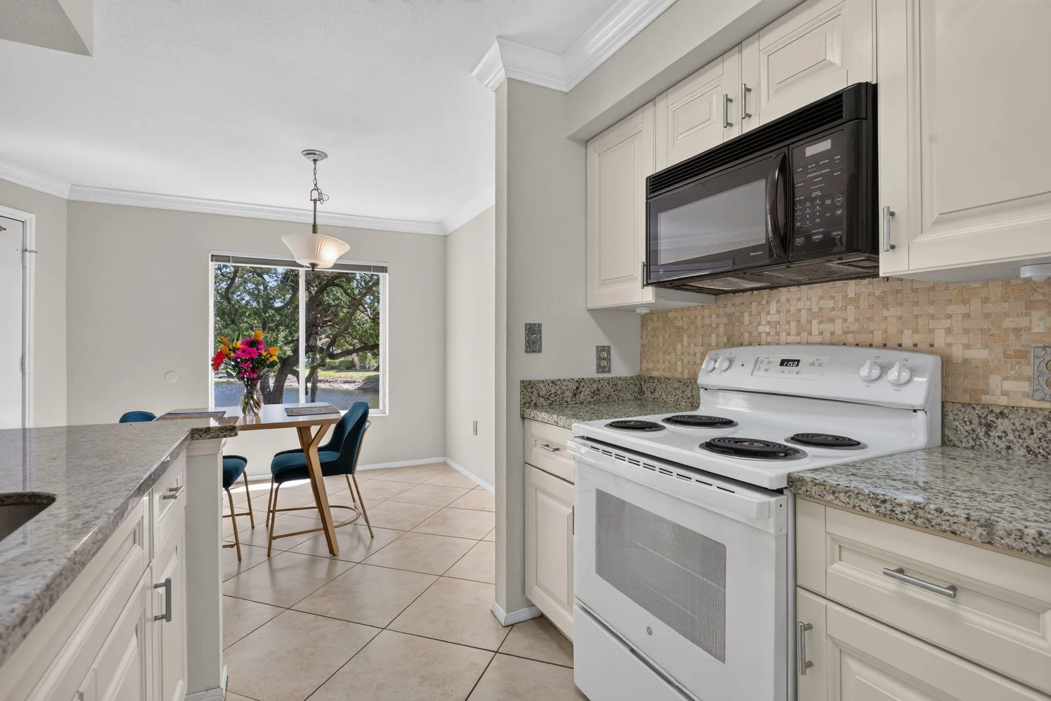 Cream shaker-style cabinetry with chrome hardware, an over-the-range microwave, and a tile backsplash