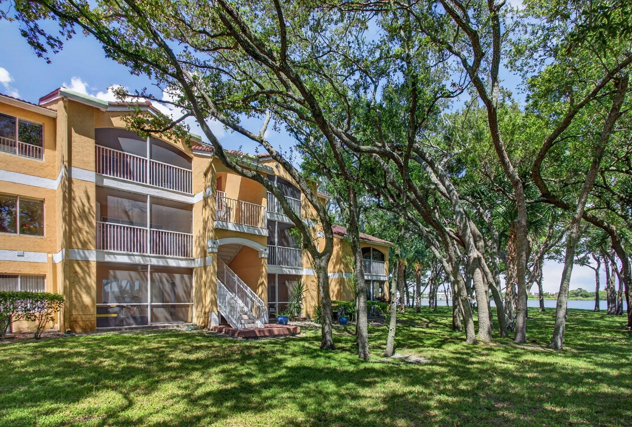 Multi-story building with textured stucco exterior, screened balconies, and white railings