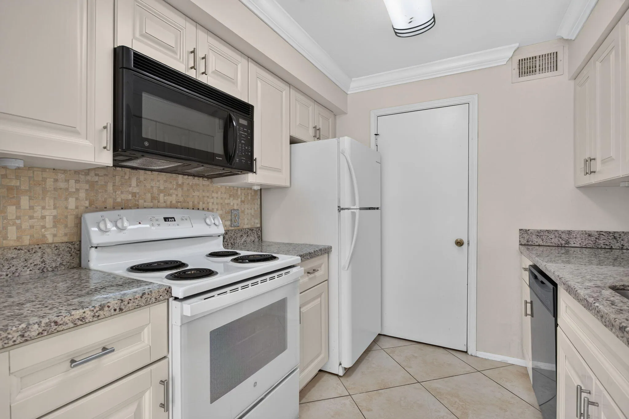 Kitchen featuring light-toned cabinetry, granite-finish countertops, and a mosaic tile backsplash