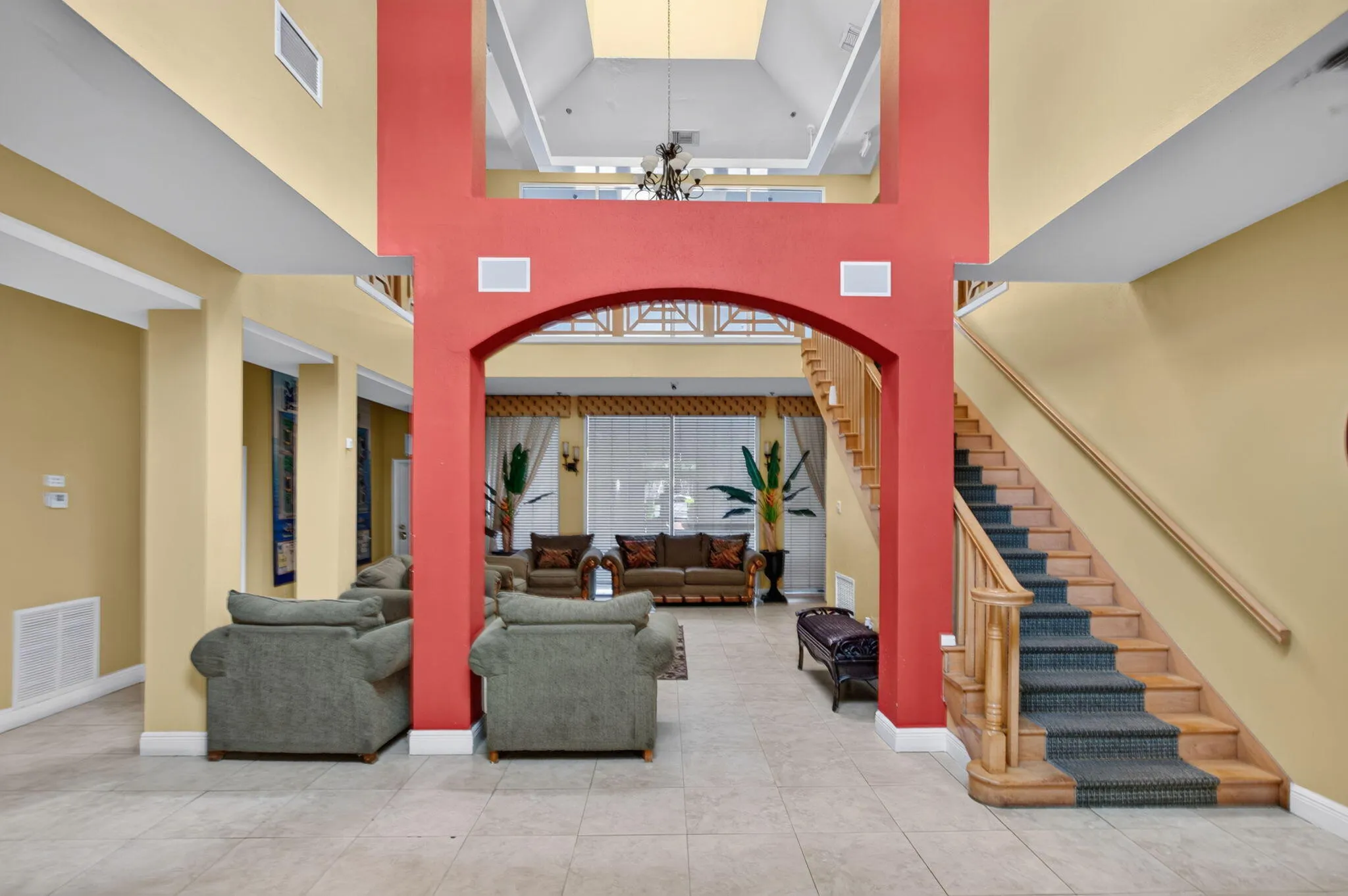 Two-story entry with arched doorway, natural wood staircase, and tile flooring