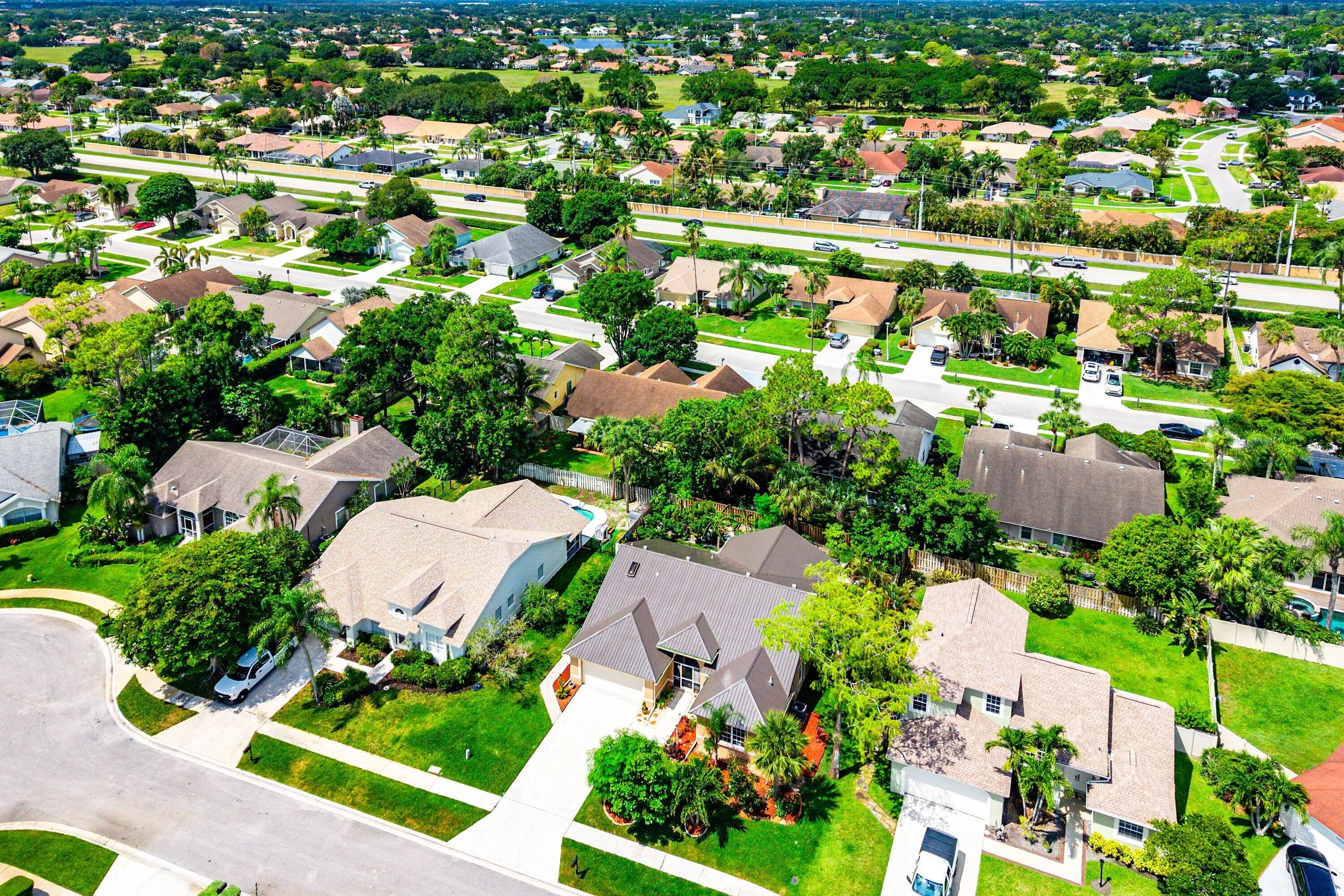Aerial neighborhood perspective featuring residential properties, mature landscaping, and an arterial road