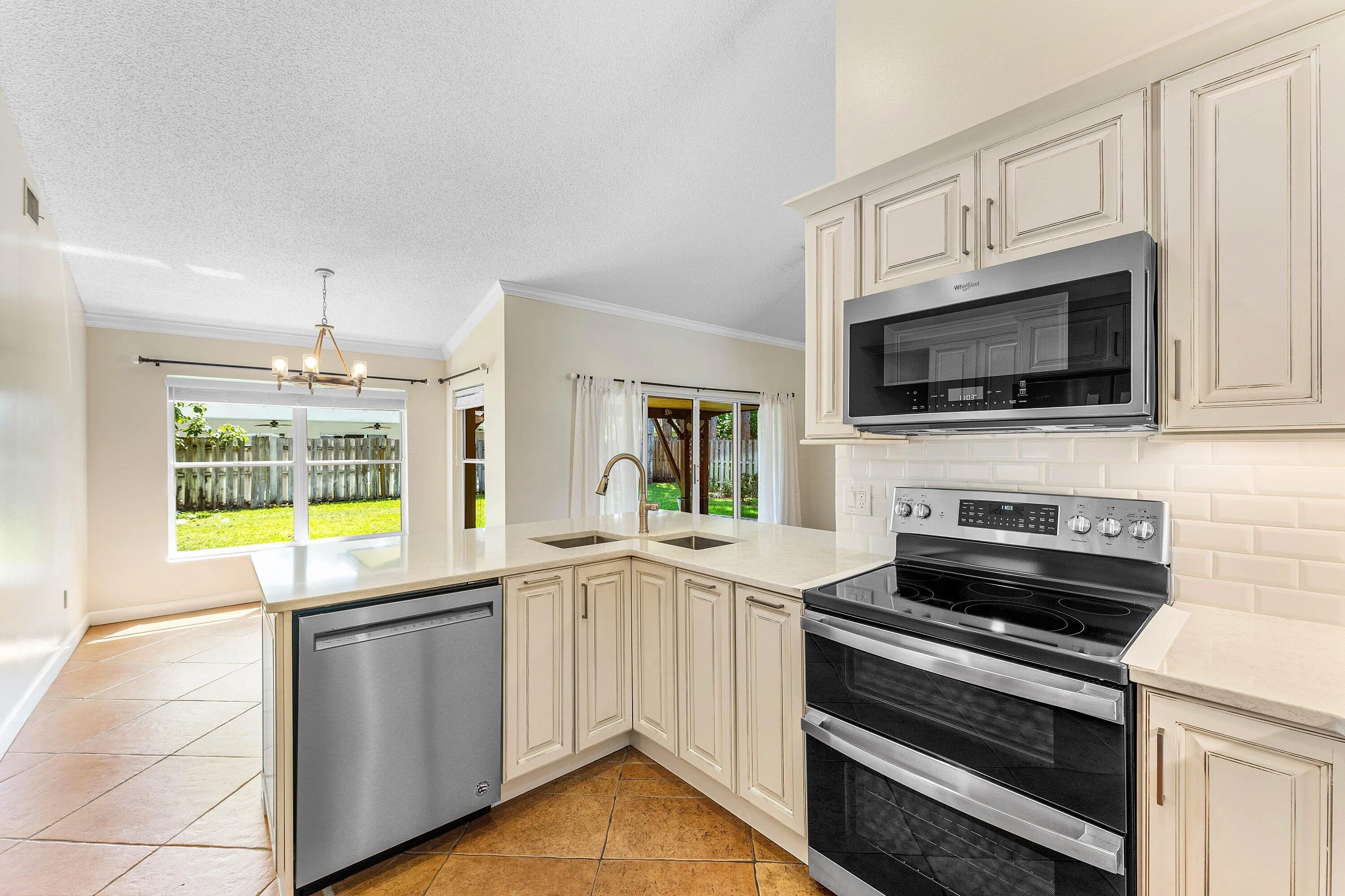 Kitchen featuring light-toned cabinetry, light countertops, subway tile backsplash, and stainless steel appliances