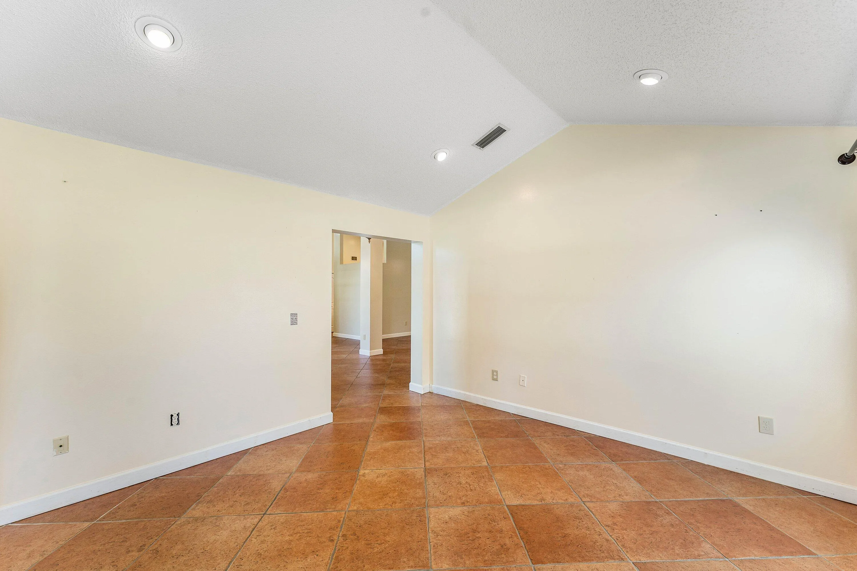 Vaulted ceiling with recessed lighting, tile flooring, and neutral wall tones