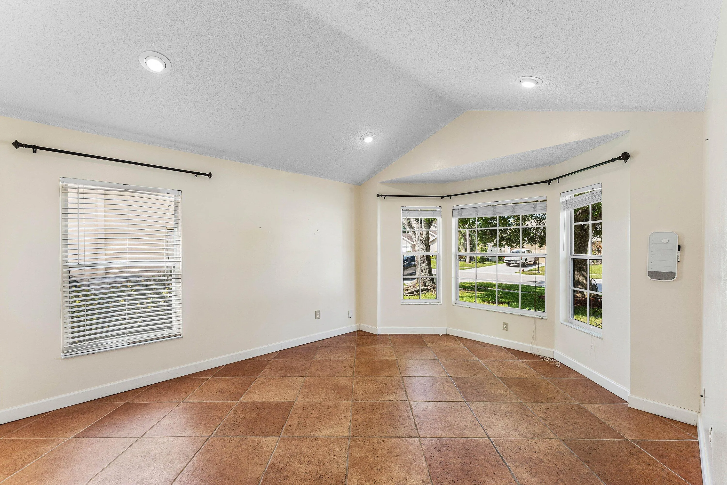 Vaulted ceiling, recessed lighting, tile flooring, and bay windows
