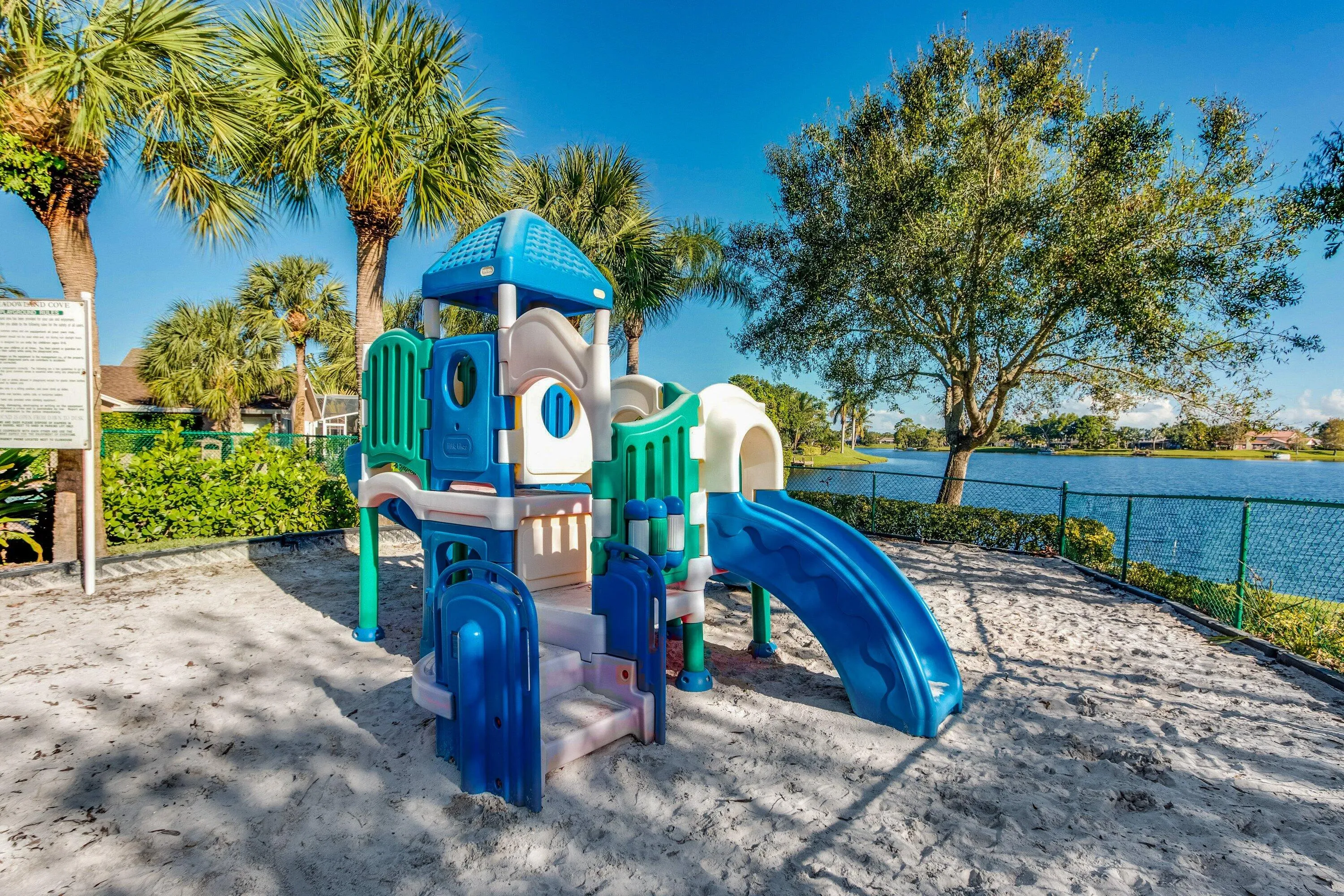 Playground structure with multiple slides and climbing elements, situated on a sand-covered area