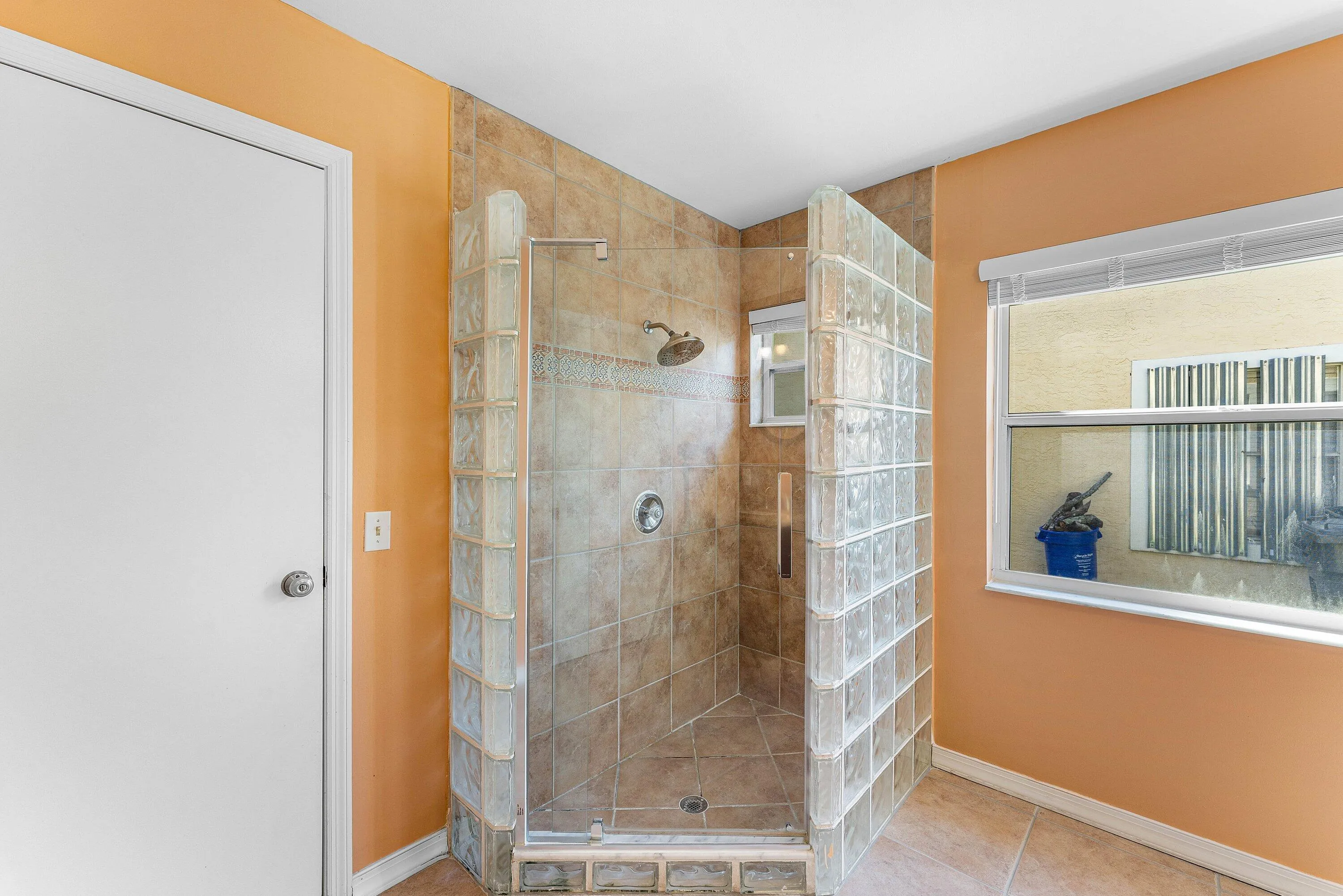 Shower enclosure with glass block wall, full-height tile surround, and an integrated shower head