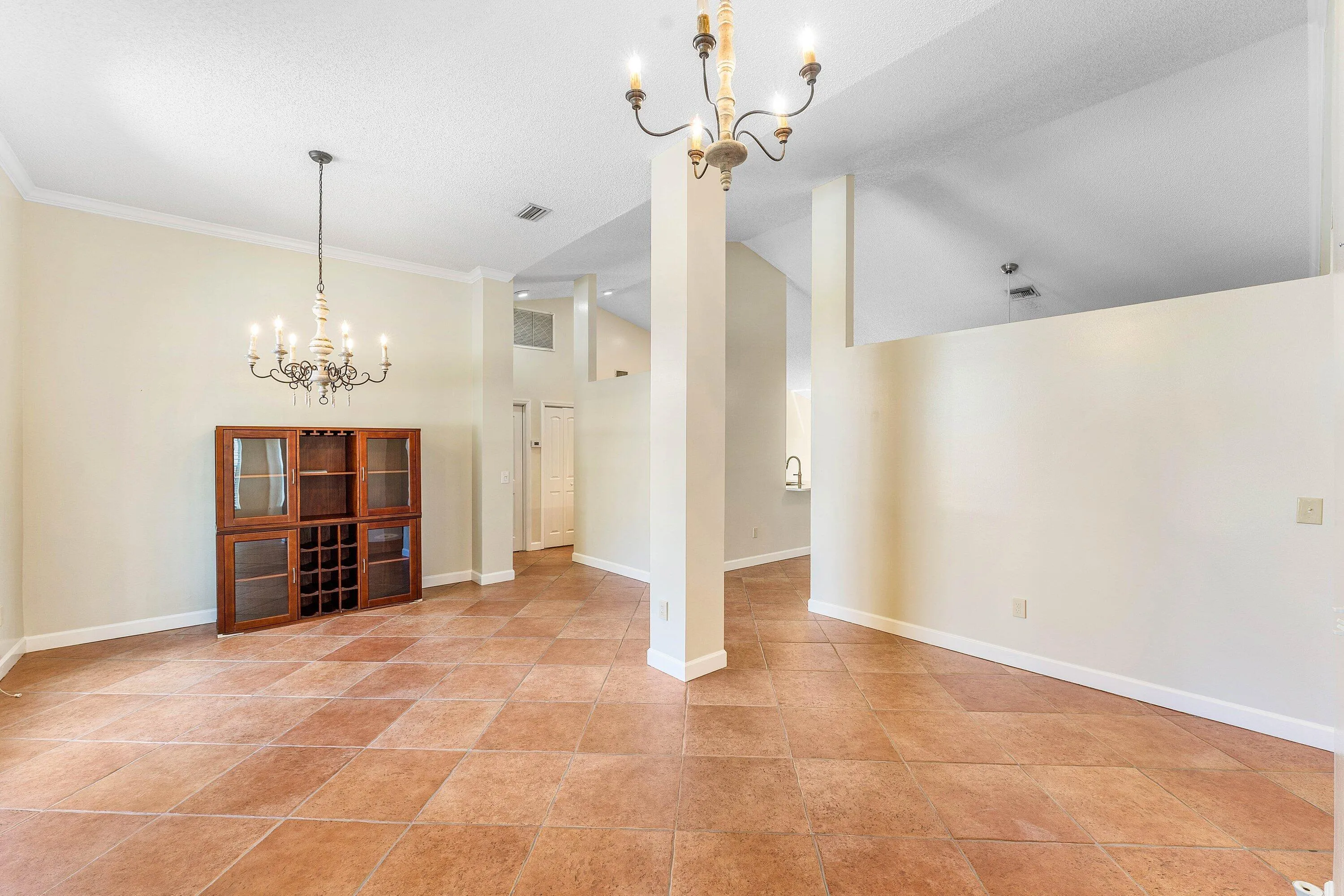 Vaulted ceilings with exposed beams, tile flooring, and multiple chandeliers