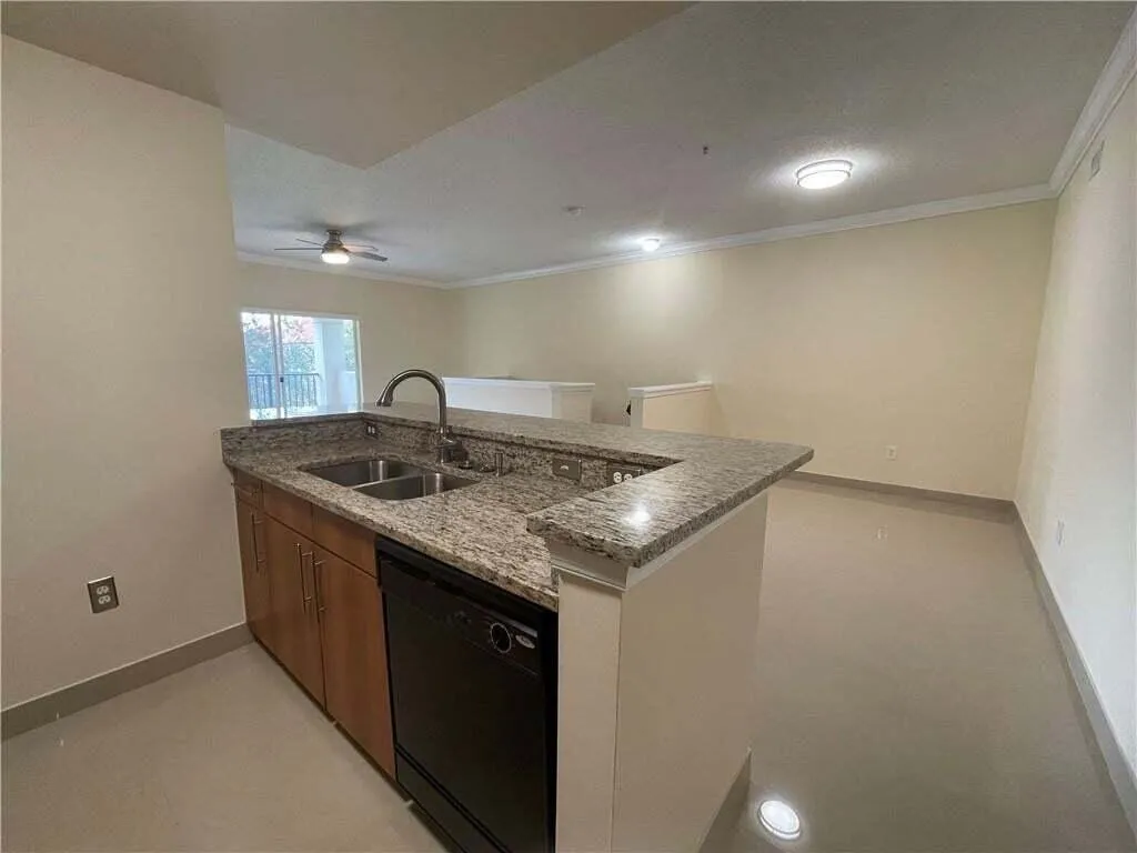 Kitchen island with granite countertops, double basin sink, and wood cabinetry