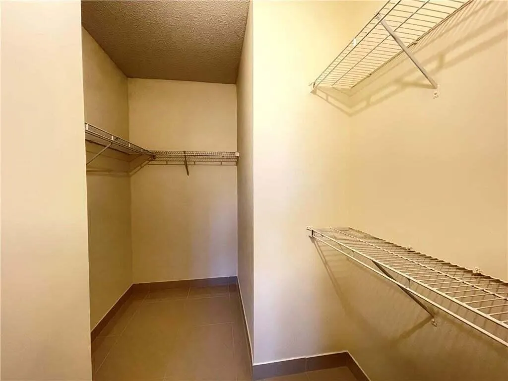 Walk-in closet featuring wire shelving, hanging rods, and tile flooring