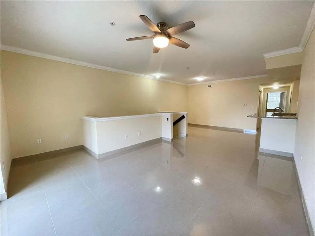 Spacious living area featuring neutral-toned walls, tile flooring, and a ceiling fan