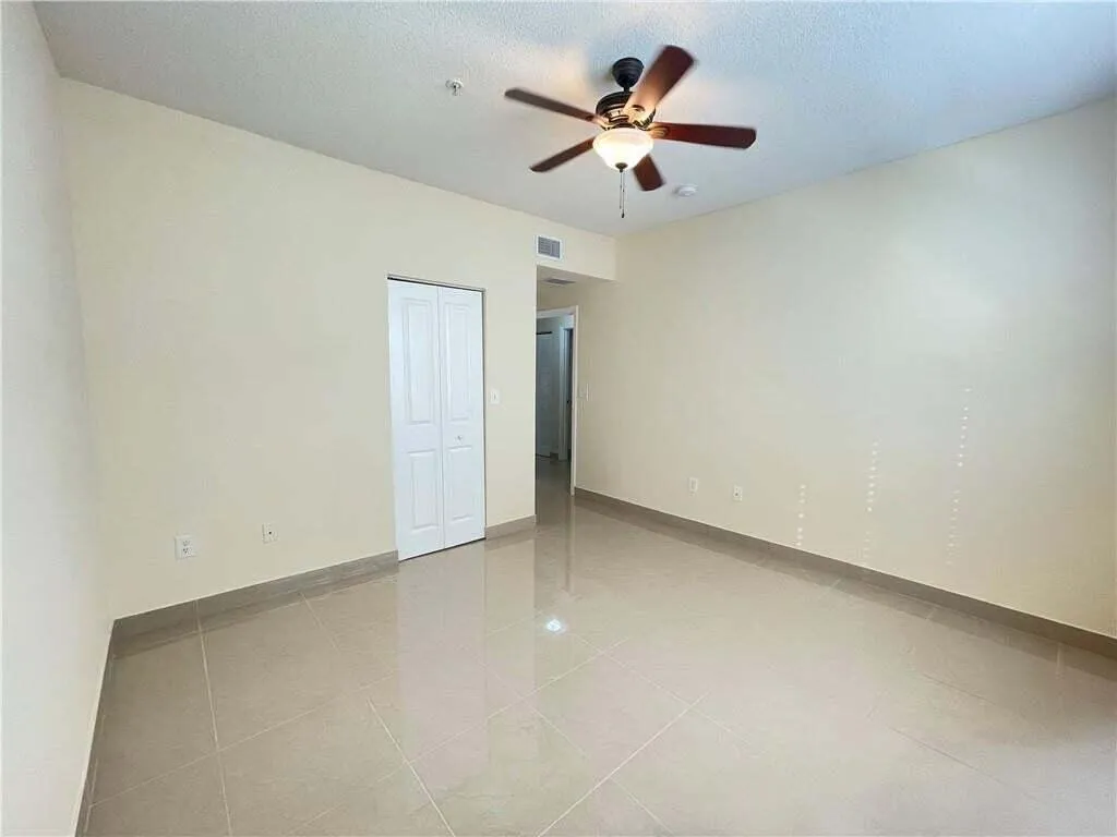 Neutral-toned tile flooring, light wall paint, and a ceiling fan with integrated lighting
