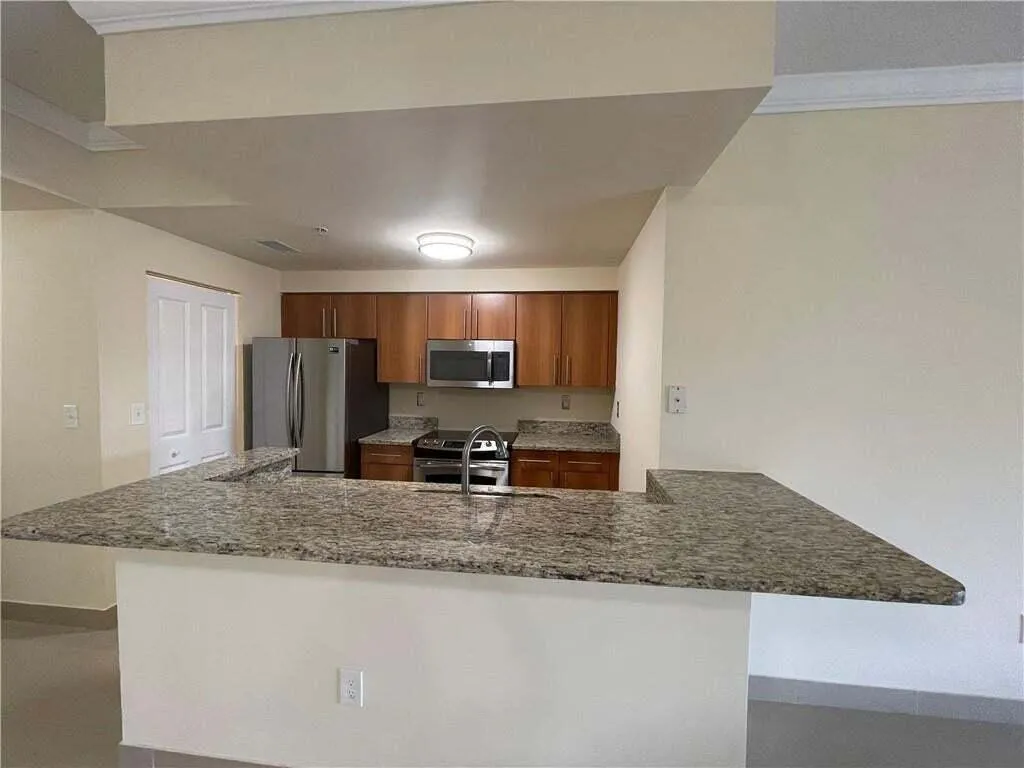 Kitchen featuring a breakfast bar with stone countertops, wood cabinetry, and stainless steel appliances