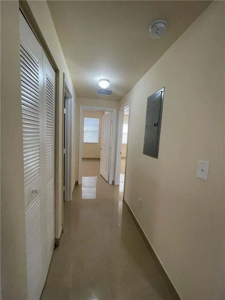 Hallway with tile flooring, louvered closet doors, and recessed lighting