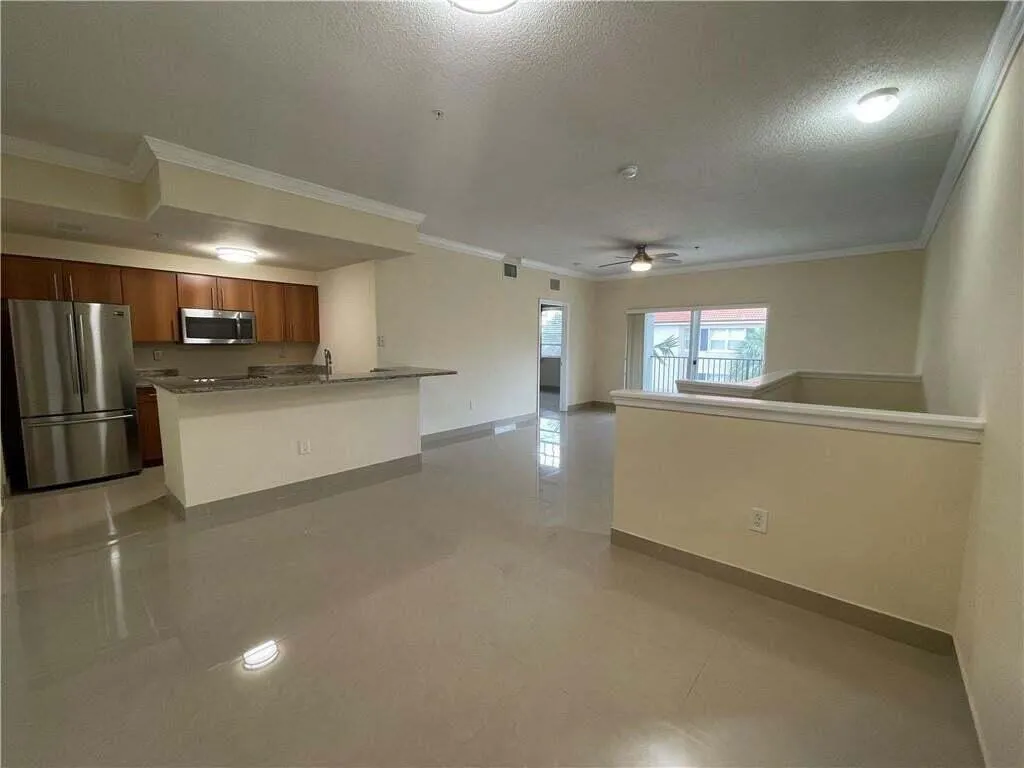 Open-concept living area featuring a kitchen with wood cabinetry, stainless steel appliances, a breakfast bar, and tile flooring throughout
