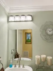Crown molding, wall-mounted vanity lighting, framed mirror, and a basin sink with a brushed nickel faucet