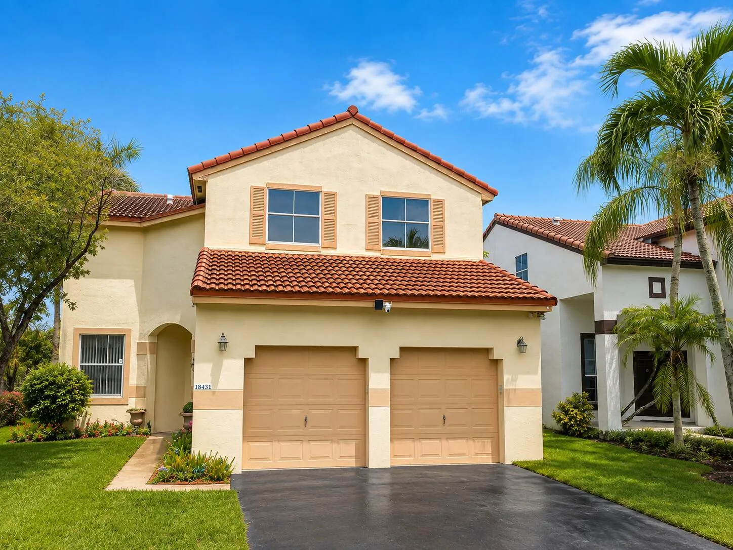 Stucco exterior with a tile roof, two-car garage, and decorative window shutters