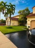 Stucco exterior with a tile roof, mature palm trees, a well-maintained lawn, and a paved driveway