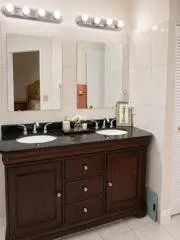 Dual vanity with dark wood-finish cabinetry, integrated sinks, and polished chrome faucets