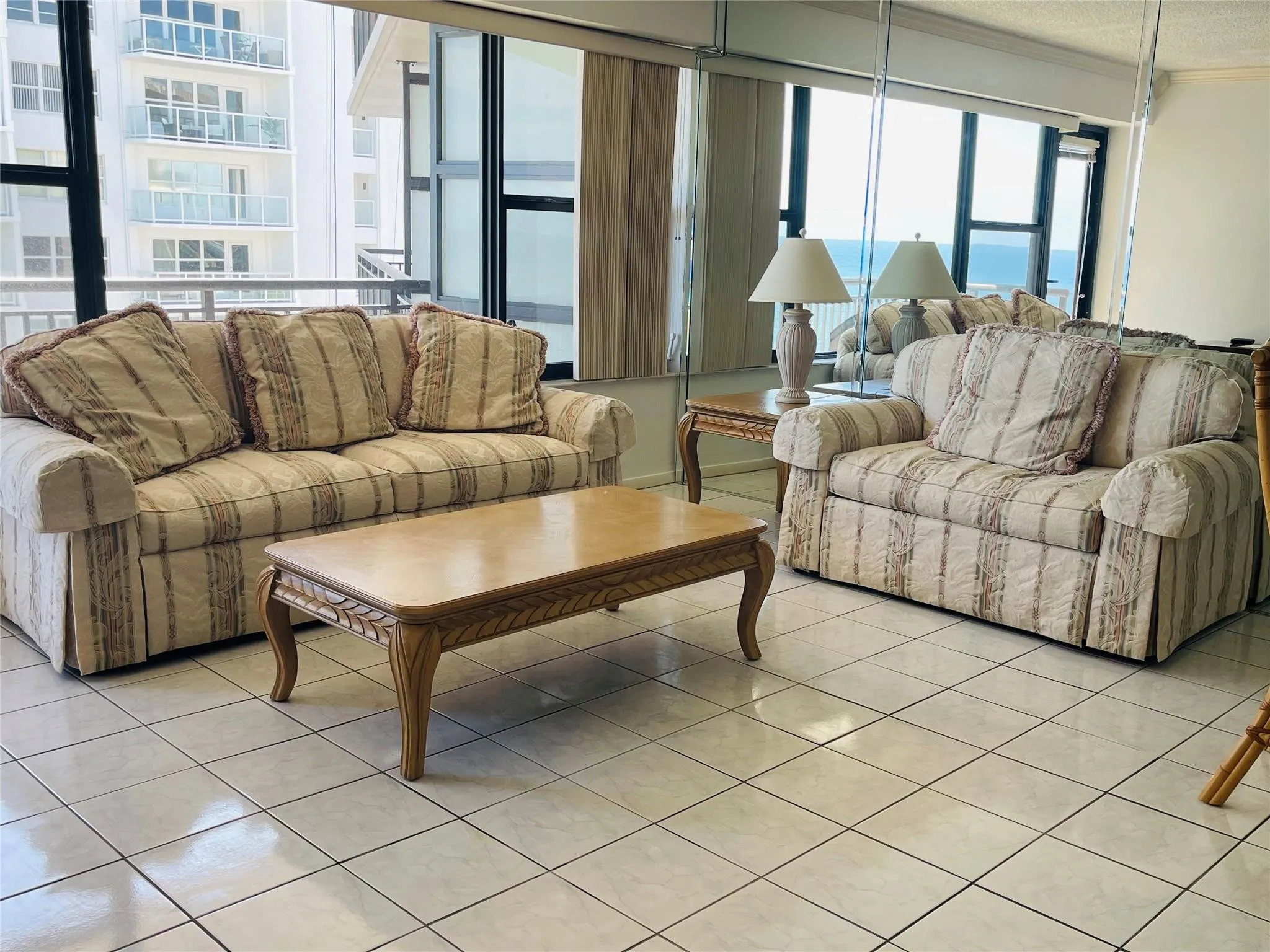 Expansive windows offering water scenery, tiled flooring, mirrored wall, and vertical blinds
