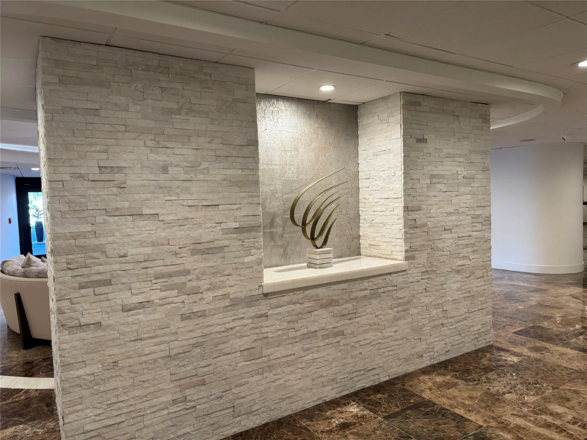 Stone veneer wall with an integrated display niche, recessed lighting, and a polished stone sill, complemented by a polished stone flooring
