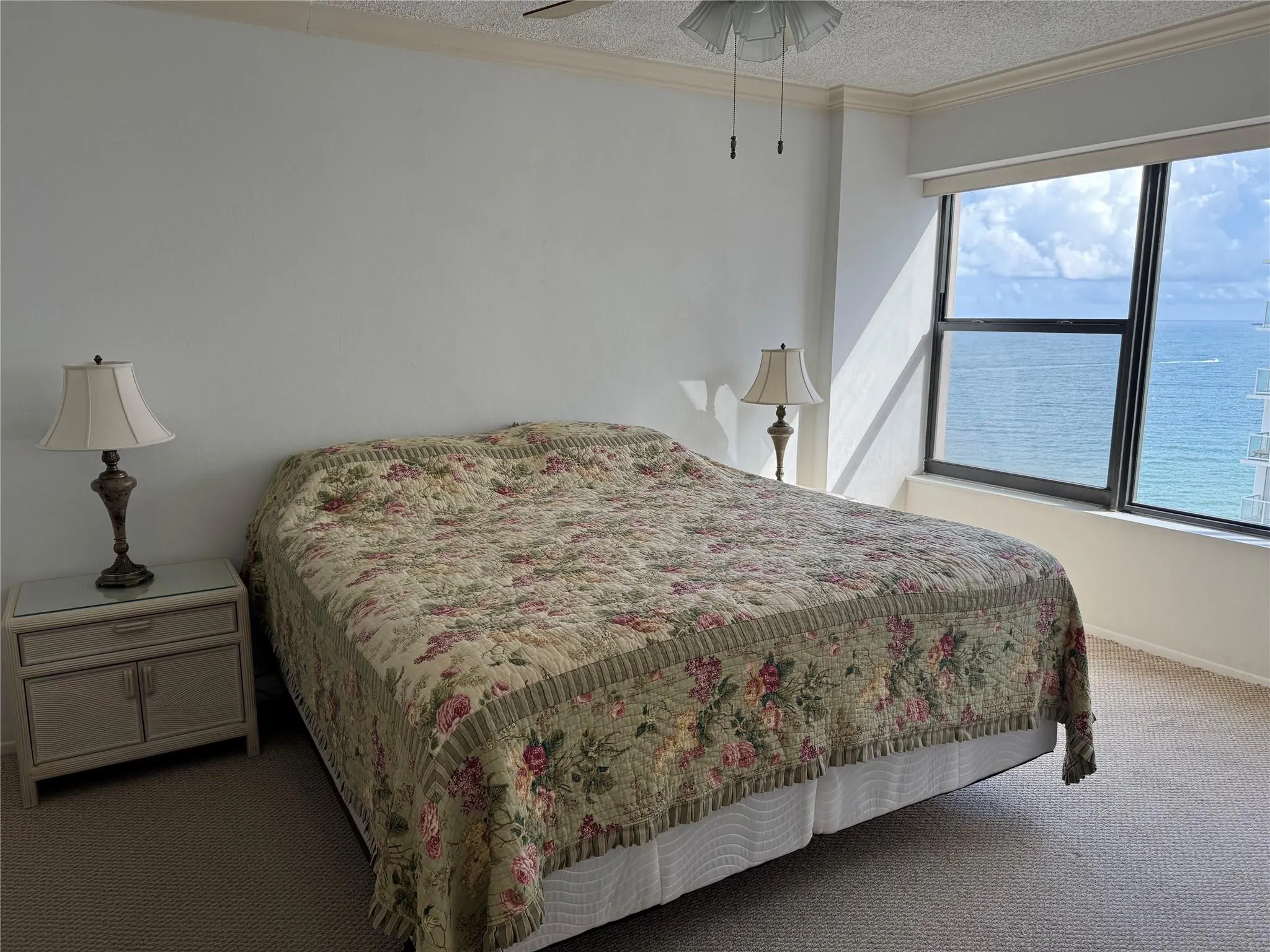 Expansive window offering ocean scenery, ceiling fan, and crown molding