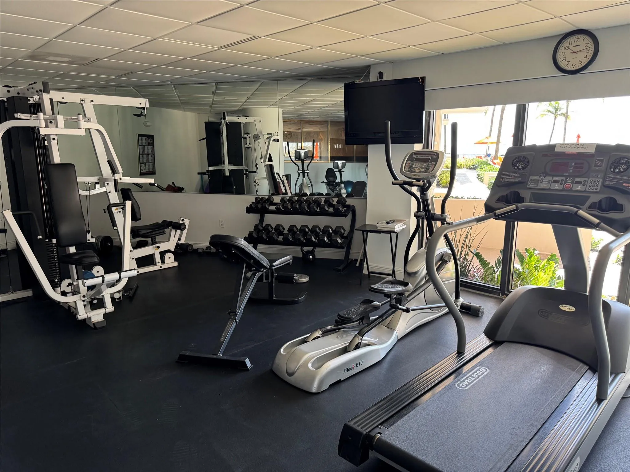 Fitness center with rubber flooring, mirrored wall, large picture windows, and drop ceiling