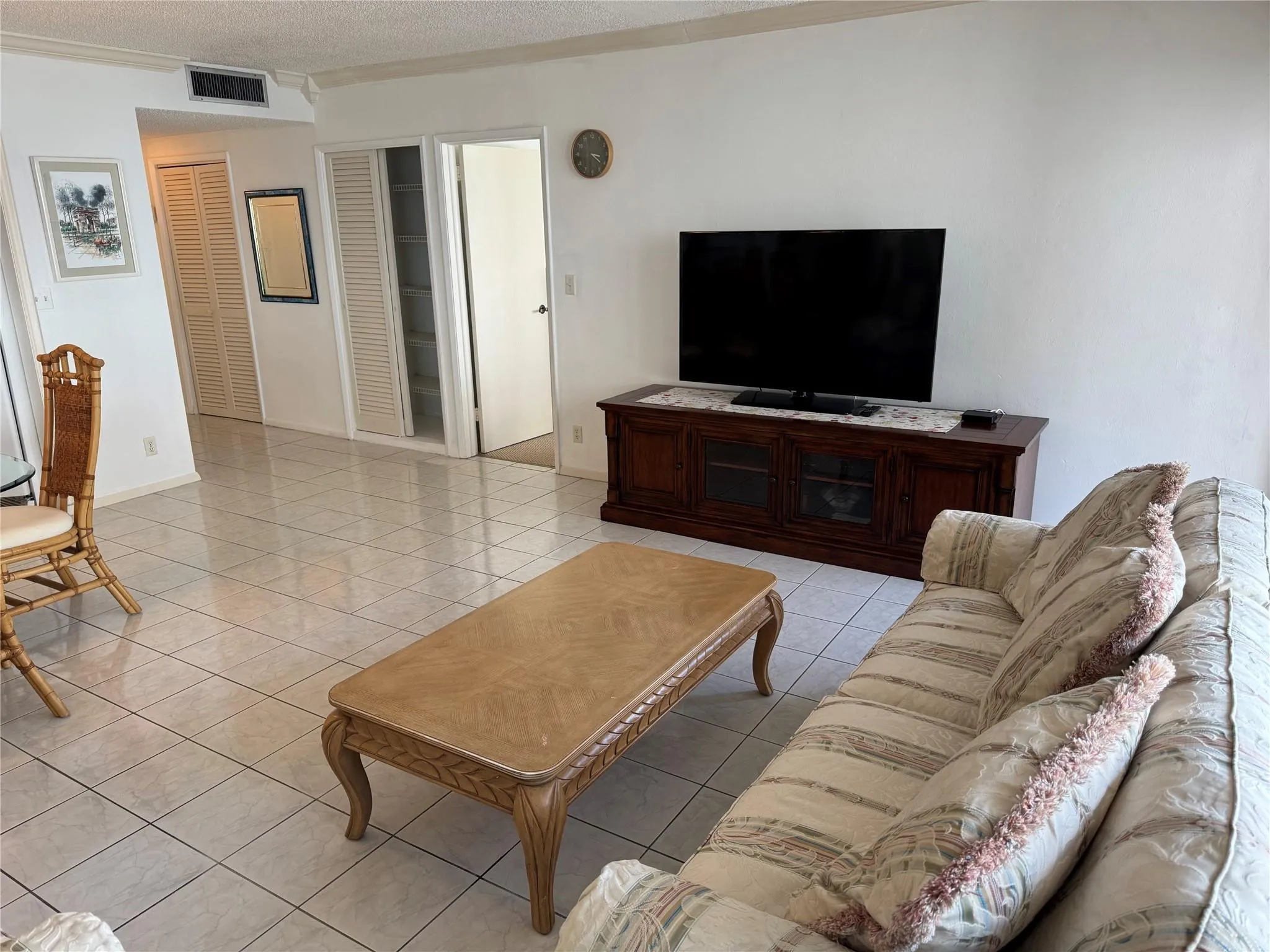 White tile flooring throughout, white walls, and a built-in wood-finish media console