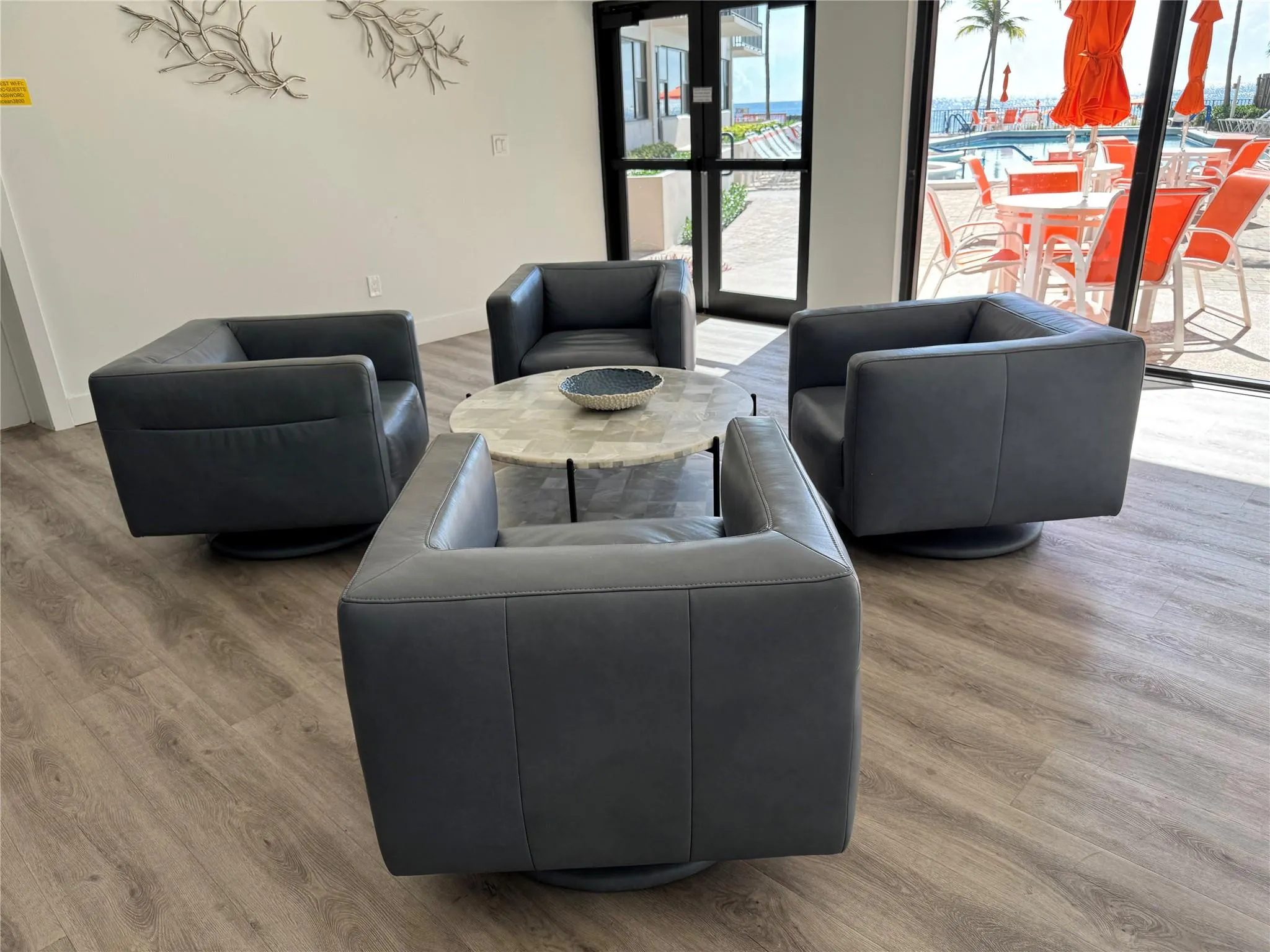 Wood-finish flooring with a light tone, full-height exterior glass panels, and a white wall finish