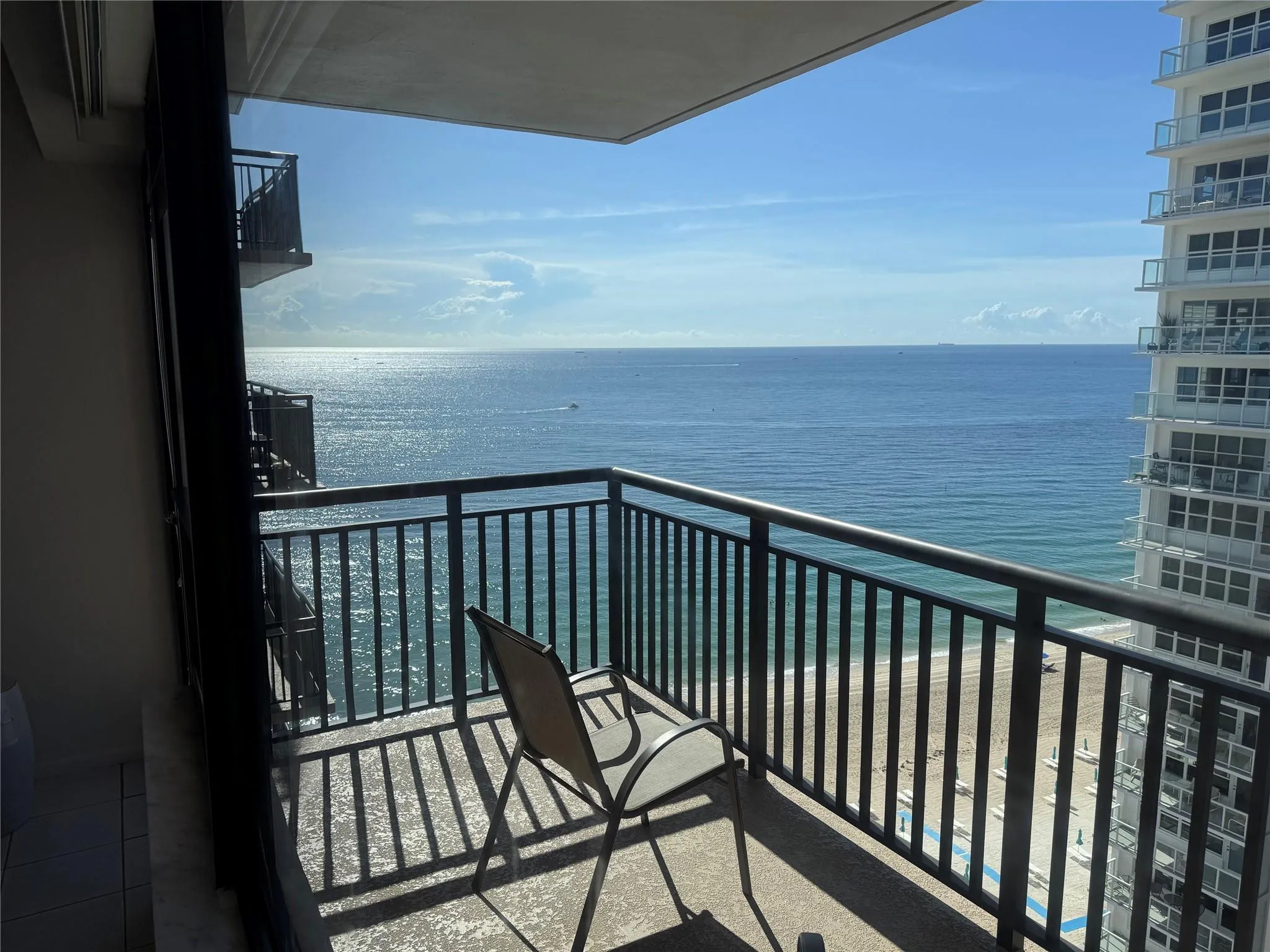 Private balcony with black metal railings overlooking ocean and beach