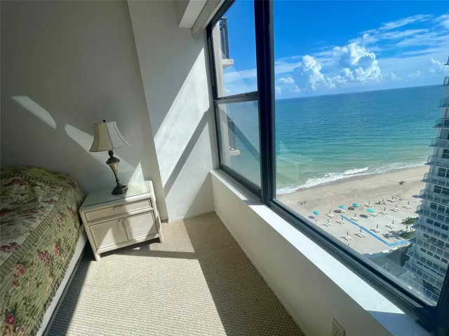 Floor-to-ceiling windows with a serene ocean and beach backdrop