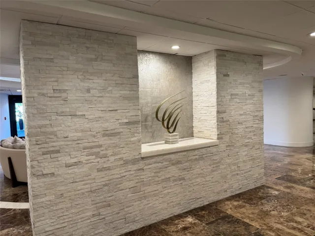 Stone veneer wall with an integrated display niche, recessed lighting, and a polished stone sill, complemented by a polished stone flooring