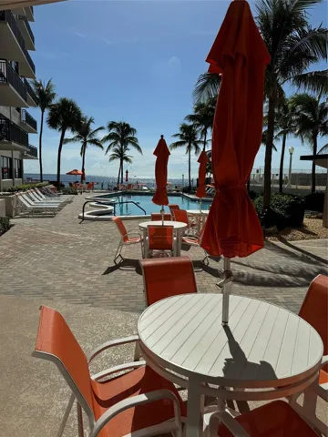 Outdoor pool area featuring a paver patio, a swimming pool with an integrated spa, and palm trees