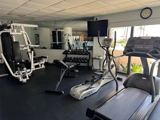 Fitness center with rubber flooring, mirrored wall, large picture windows, and drop ceiling