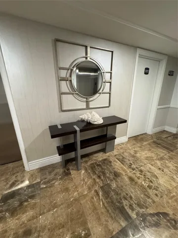 Marbled tile flooring, textured wall covering, decorative wall mirror, and a wood-finish console table