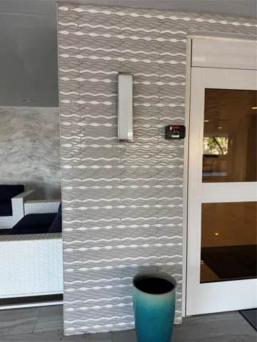 Textured tile wall detailing a wave pattern, integrated wall sconce, and a secure entry system