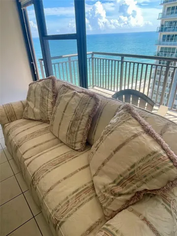 Floor-to-ceiling glass doors opening to a private balcony with metal railings and ocean backdrop